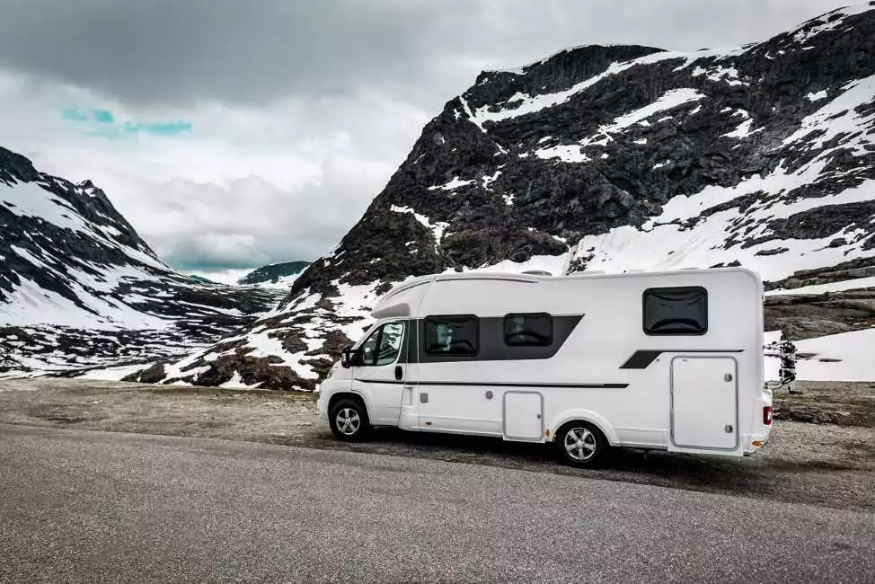 An RV drives through a winter landscape.