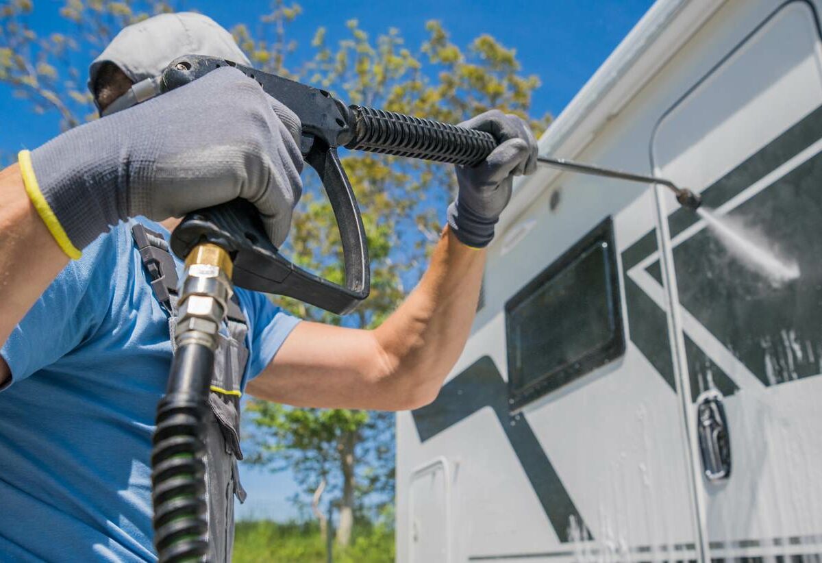A man cleaning his RV with a power washer
