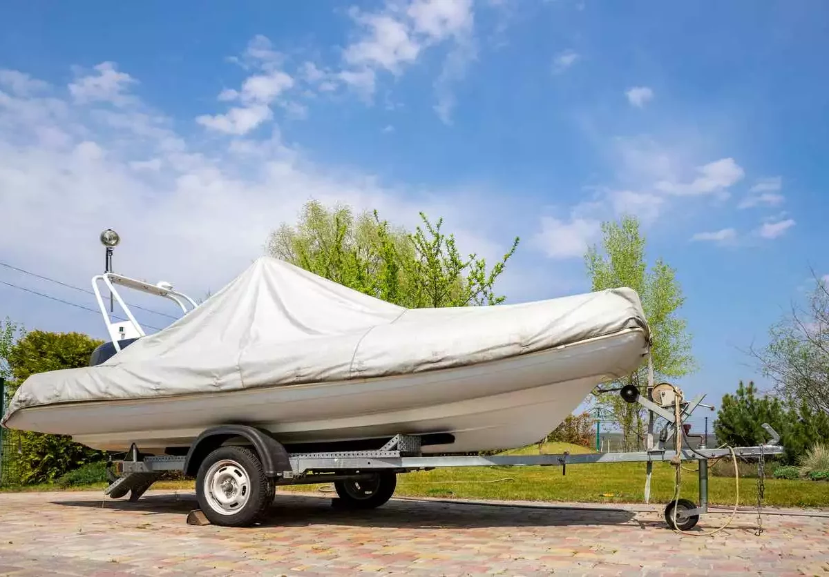 A boat sitting on top of a trailer, covered by a tarp