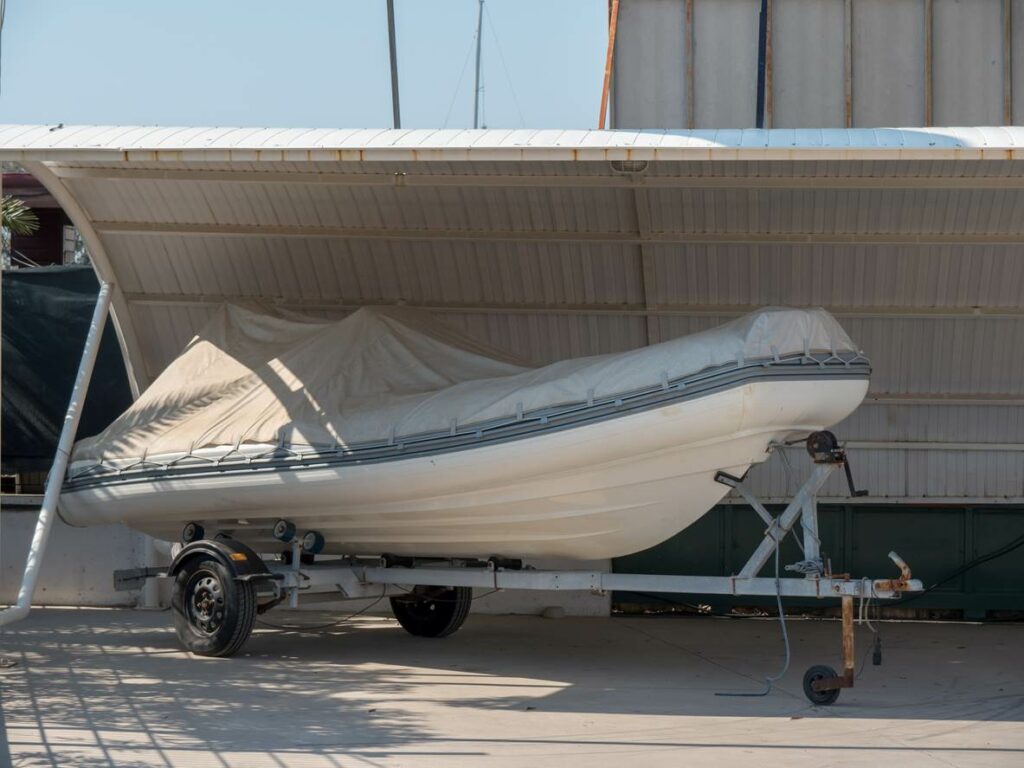 A motorboat covered by a tarp sits underneath a metal awning