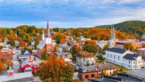 A small town scene with many small buildings, churches, homes, and stores with fall foliage