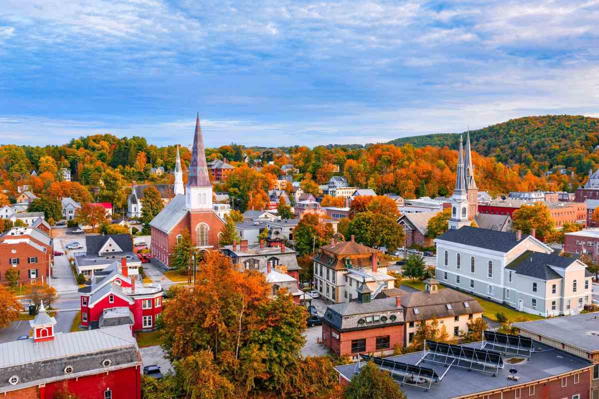 A small town scene with many small buildings, churches, homes, and stores with fall foliage