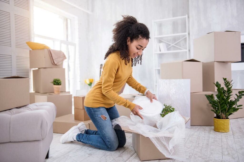 A woman placing delicate dishes in a storage box.