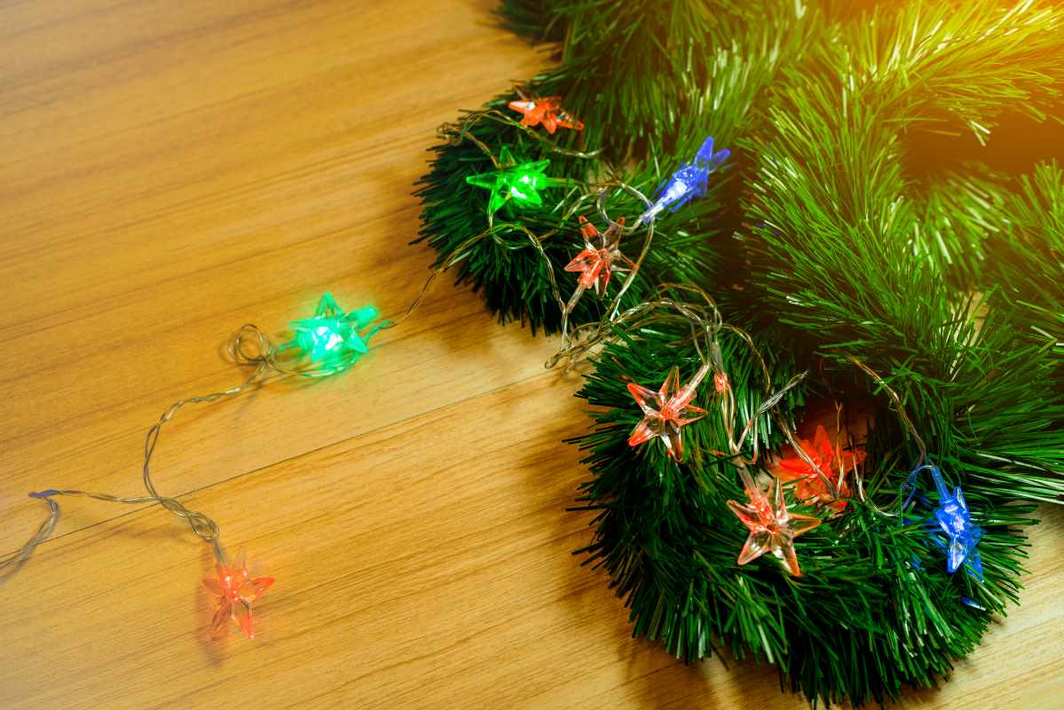 Strands of Christmas garland spread across a wood table. 