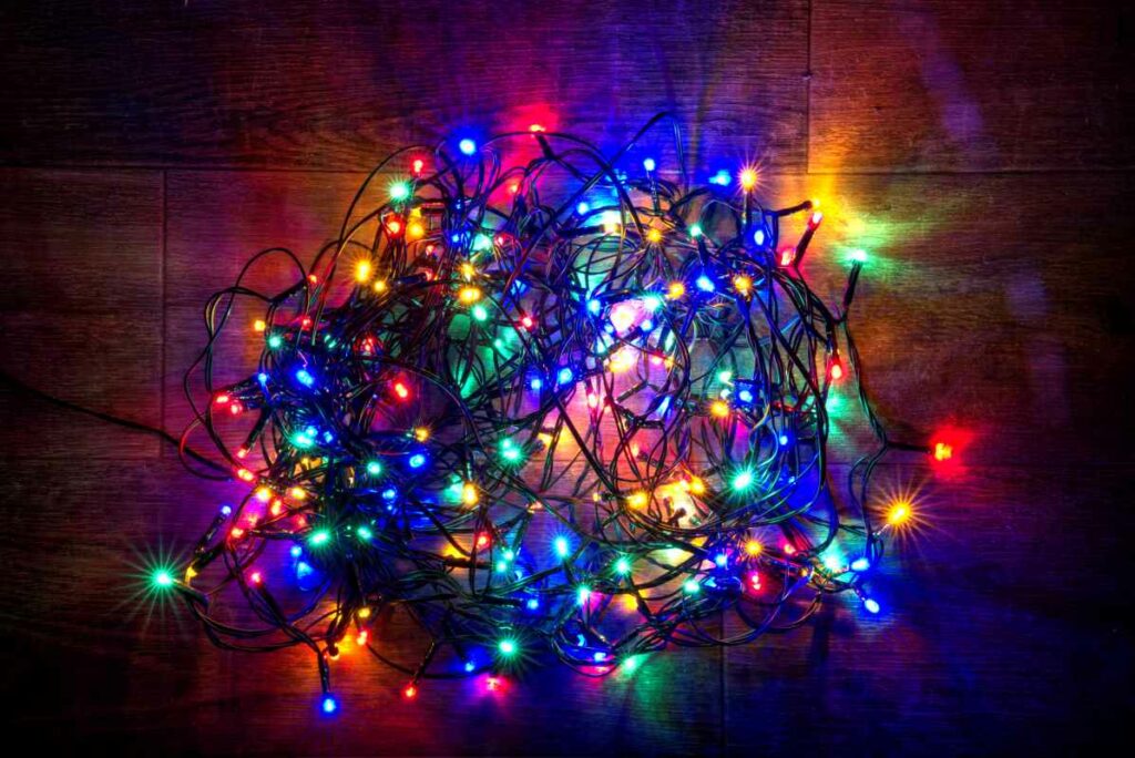 A strand of multicolor Christmas lights sits, coiled in a cardboard box.