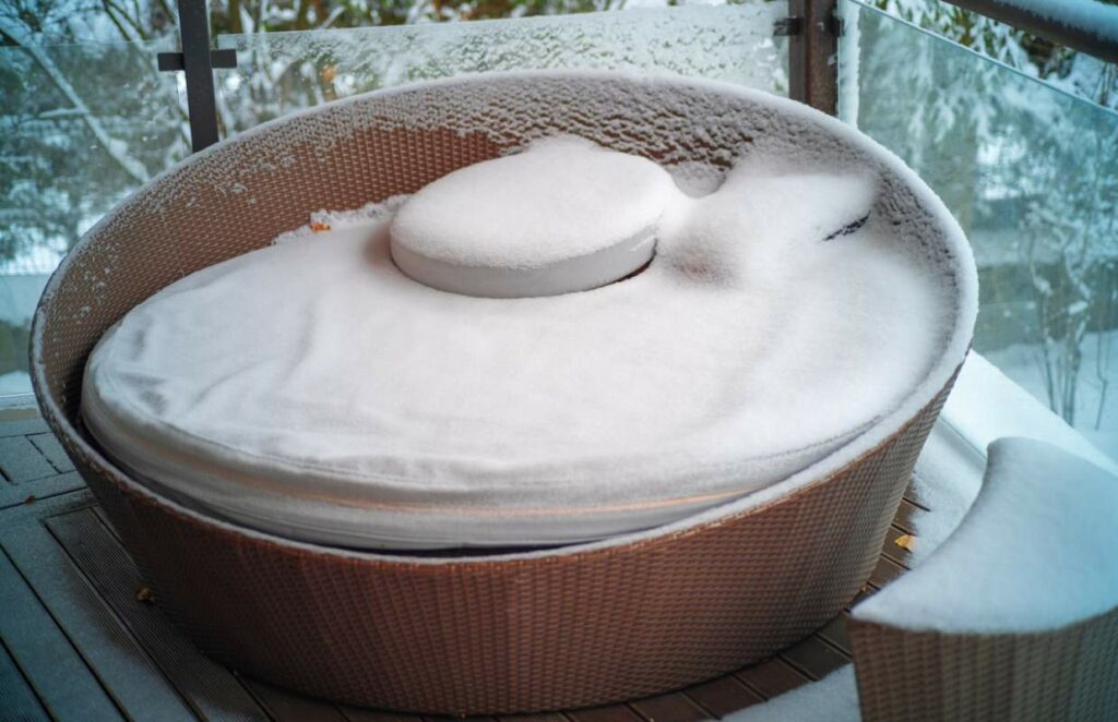 Outdoor armchair and pillow covered in snow. 