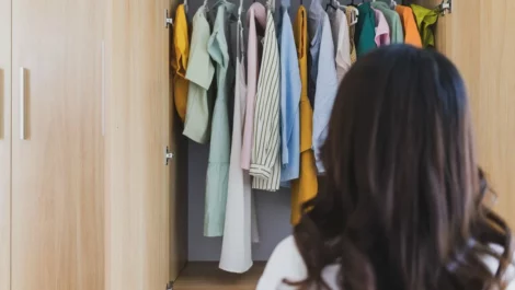 A young woman looking at her full wardrobe.