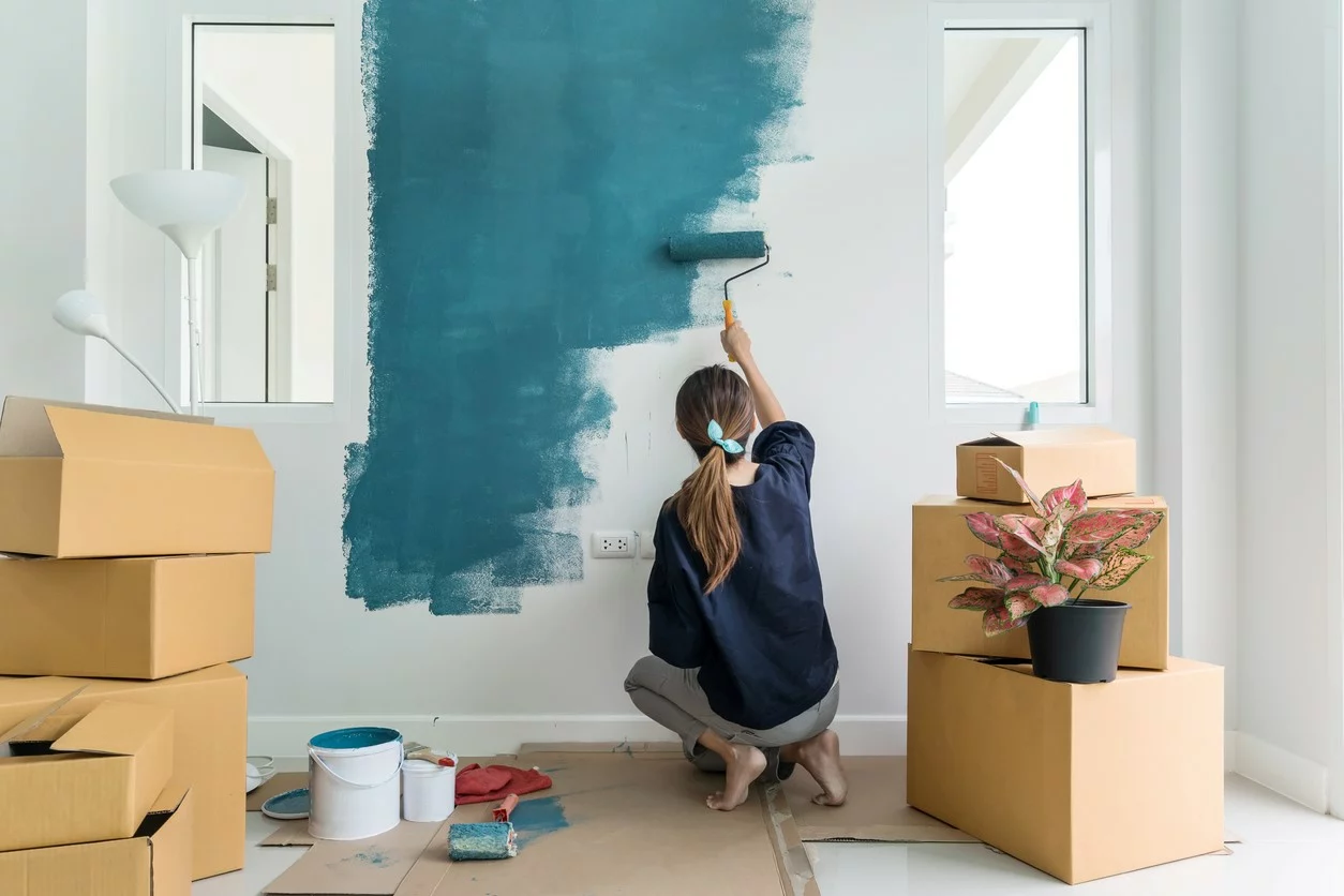 A young woman painting walls of her decluttered home.