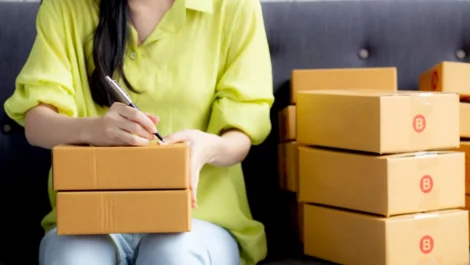 A young woman on her couch labeling boxes for her storage unit