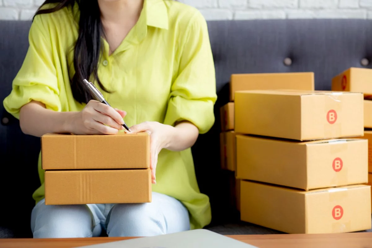 A young woman on her couch labeling boxes for her storage unit