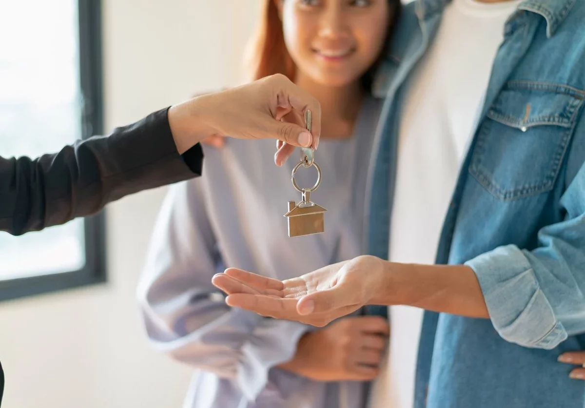 A young couple receiving keys to their new house.