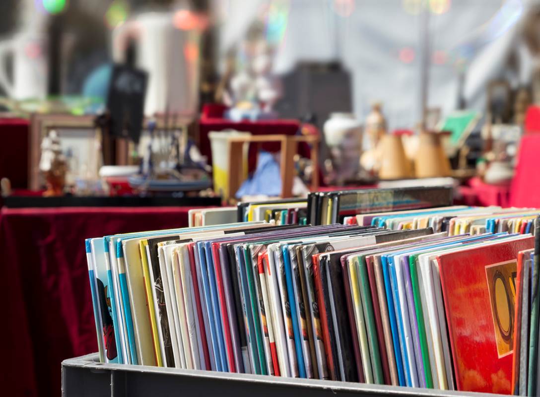 A collection of records on a shelf at a flea market.