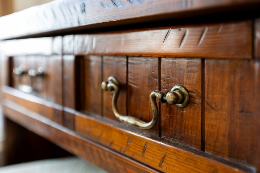 A close-up of the iron handle of an antique wooden drawer.