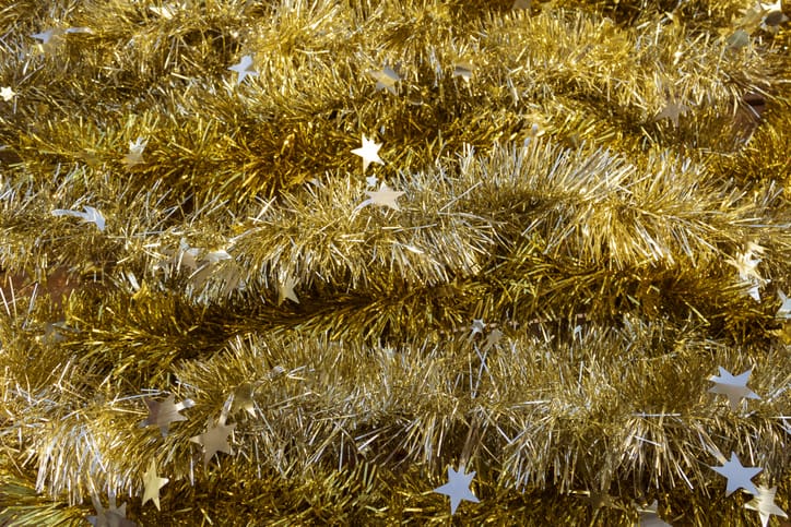 A Christmas garland with stars and gold tinsel is coiled.