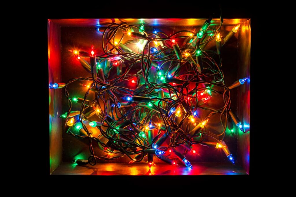 A strand of multicolor Christmas lights sits, coiled in a cardboard box.